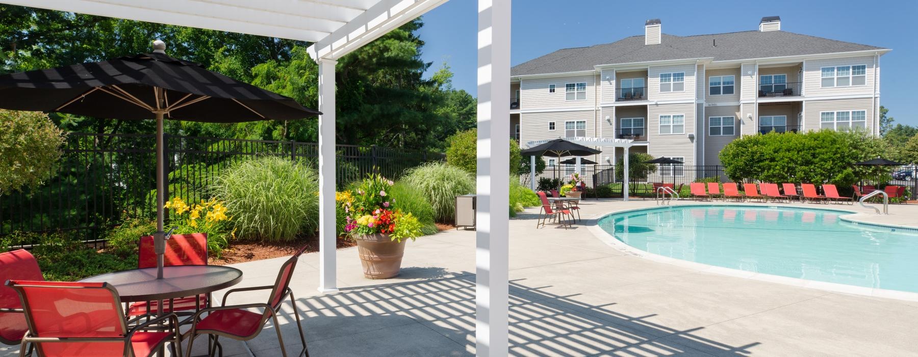 a pool with a patio and umbrellas next to it